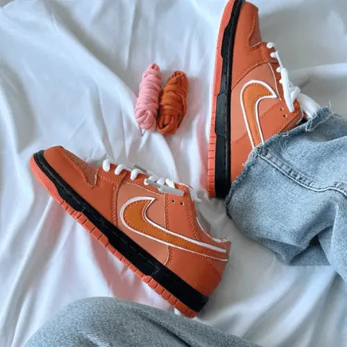 La Nike SB Dunk Low Concepts Orange Lobster portée avec un jean bleu clair.