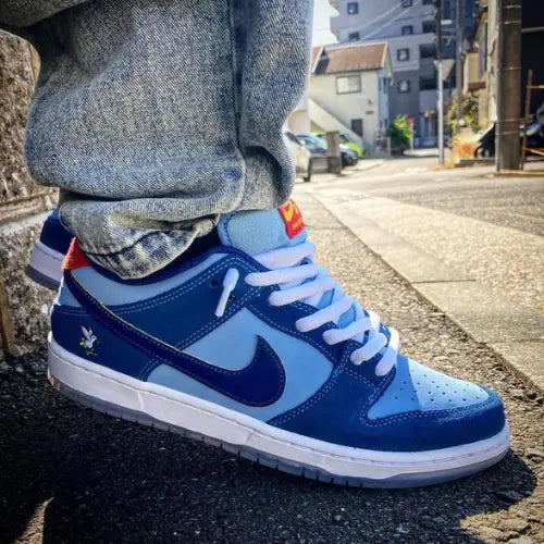 La Nike SB Dunk Low Pro Why So Sad? portée avec un pantalon gris.
