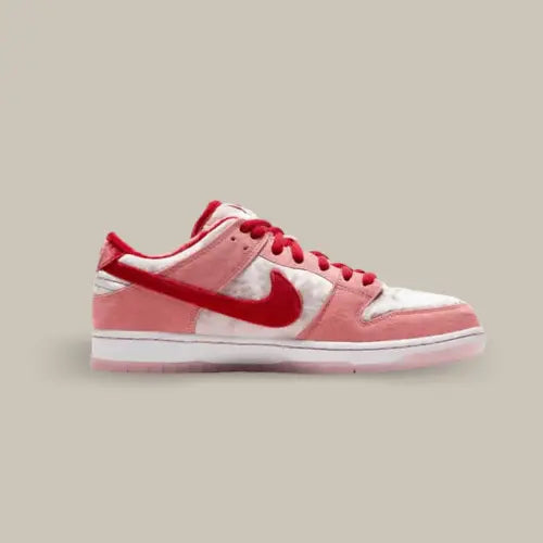 La Nike SB Dunk Low StrangeLove de coté avec son velours rouge, rose et blanc et sa tete de mort en forme de cœur sur le talon