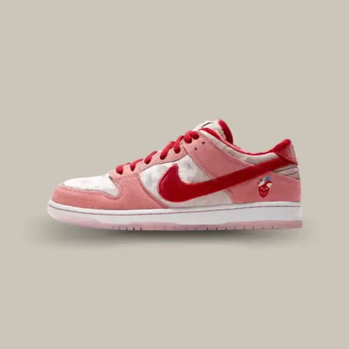 La Nike SB Dunk Low StrangeLove de coté avec son velours rouge, rose et blanc et sa tete de mort en forme de cœur sur le talon