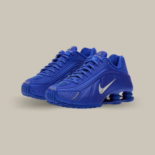 Paire de Nike Shox R4 Racer Blue Metallic Silver bleue avec Swoosh argenté et colonnes Shox, vue de trois quarts – OFFSNEAKZ.