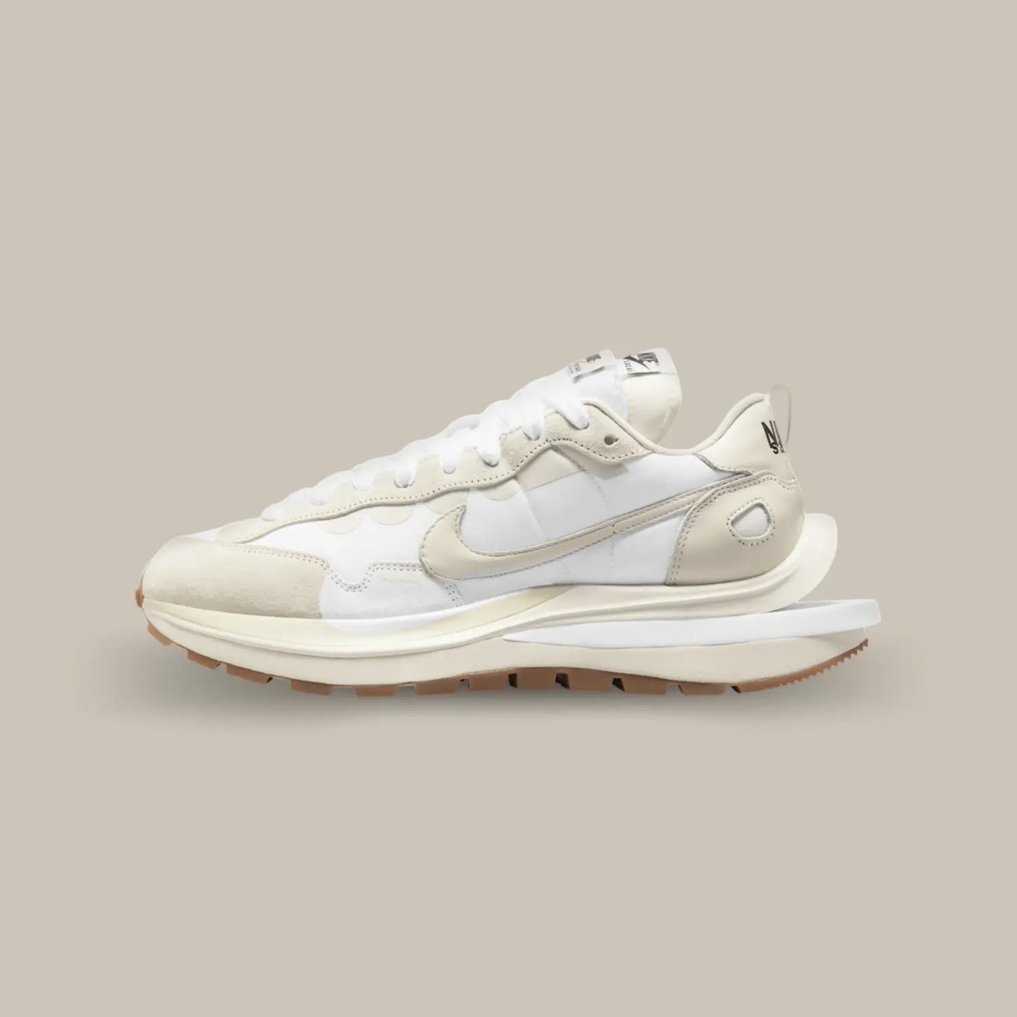 La Nike Vaporwaffle Sacai Sail Gum de coté avec un design composé de superpositions de matières et d’éléments dédoublés. Le upper joue sur une palette de couleurs très proches les unes des autres avec du blanc et blanc cassé, ce qui donne une allure élégante et sophistiquée à cette itération.