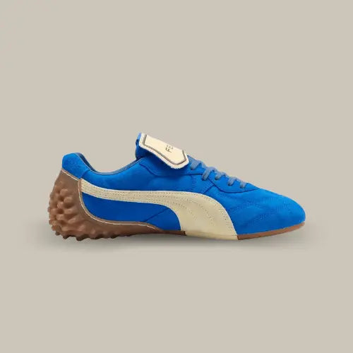 La Puma Avanti LS Fenty Team Royal vue de côté avec sa base en daim bleu royal et sa bande Puma blanche. On retrouve la languette retournée de couleur blanche et une semelle à crampons en caoutchouc qui remonte au niveau du talon.