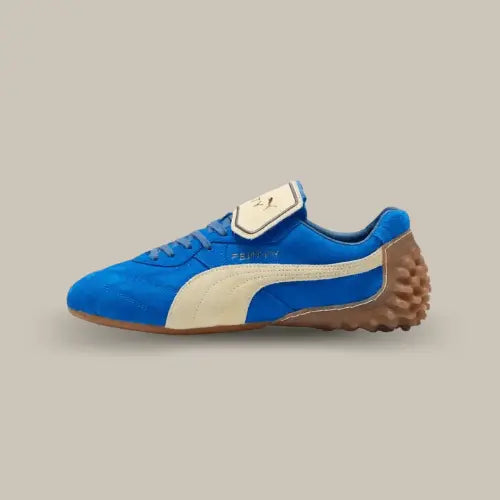 La Puma Avanti LS Fenty Team Royal vue de côté avec sa base en daim bleu royal et sa bande Puma blanche. On retrouve la languette retournée de couleur blanche, le logo Fenty au dessus de la bande et une semelle à crampons en caoutchouc qui remonte au niveau du talon.