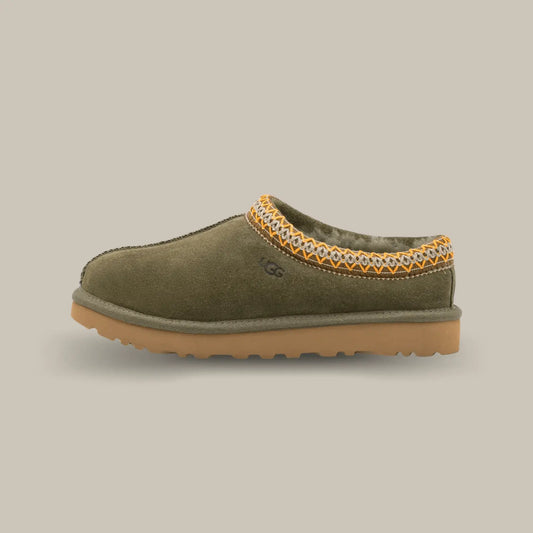 La Ugg Tasman Slipper Burnt Olive Gum de coté avec sa tige en daim vert olive, son tressage en polyester recyclé jaune et blanc et sa semelle en EVA.