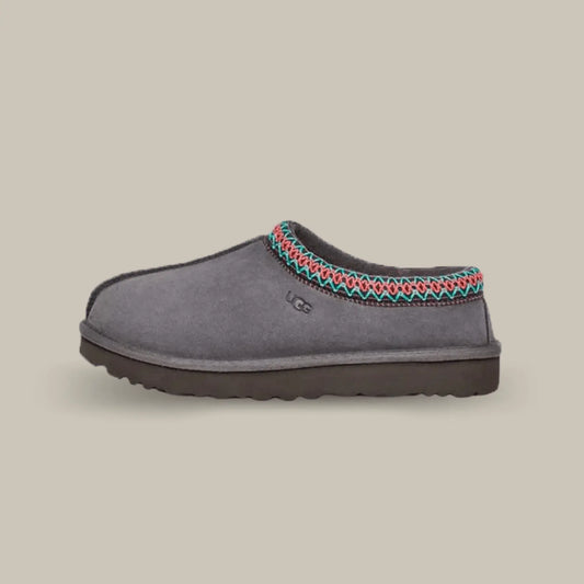 La UGG Tasman Slipper Dark Grey de coté avec sa tige en daim gris et son tressage en polyester recyclé rouge et vert.