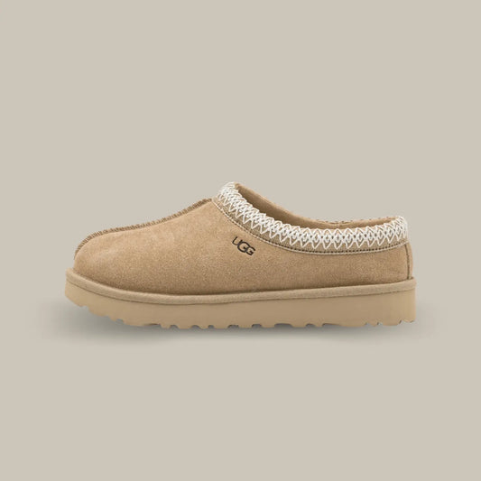 La Ugg Tasman Slipper Mustard Seed de coté avec son empeigne en daim couleur graine de moutarde et son tressage en polyester recyclé moutarde et blanc.