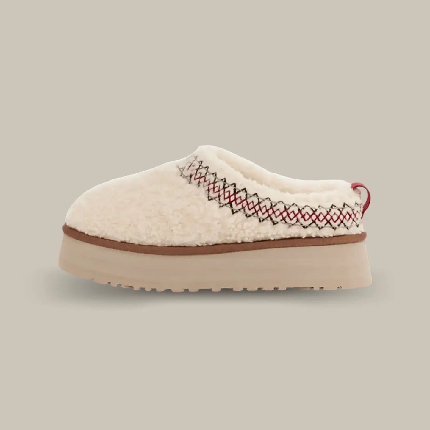 Ugg nous propose une version duveteuse avec une nouvelle tige doublée en duvet beige.  La UGG Tazz Braid Natural est également composée d’une tresse rouge et noir en polyester recyclée. On retrouve la doublure en UGGPLUSH qui est une laine recyclée combinée à de la peau de mouton. Et pour finir la célèbre semelle compensée en EVA de 4.4 cm pour un maintien optimum.